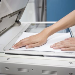 woman hands putting a sheet of paper into a copying device