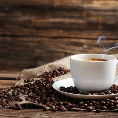 Cup of coffee with coffee beans on a brown wooden background